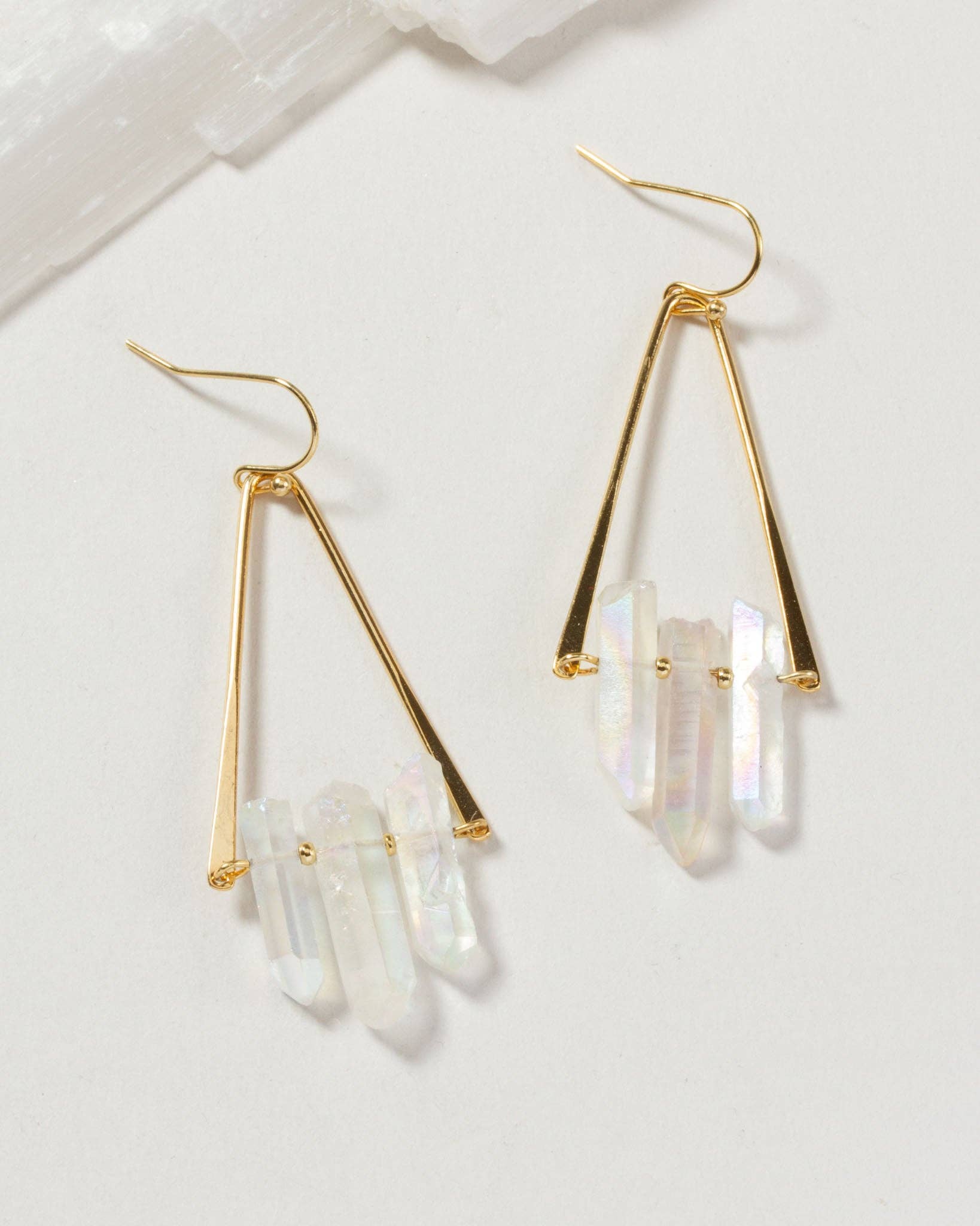 Gold earrings with clear crystal stones on a light background