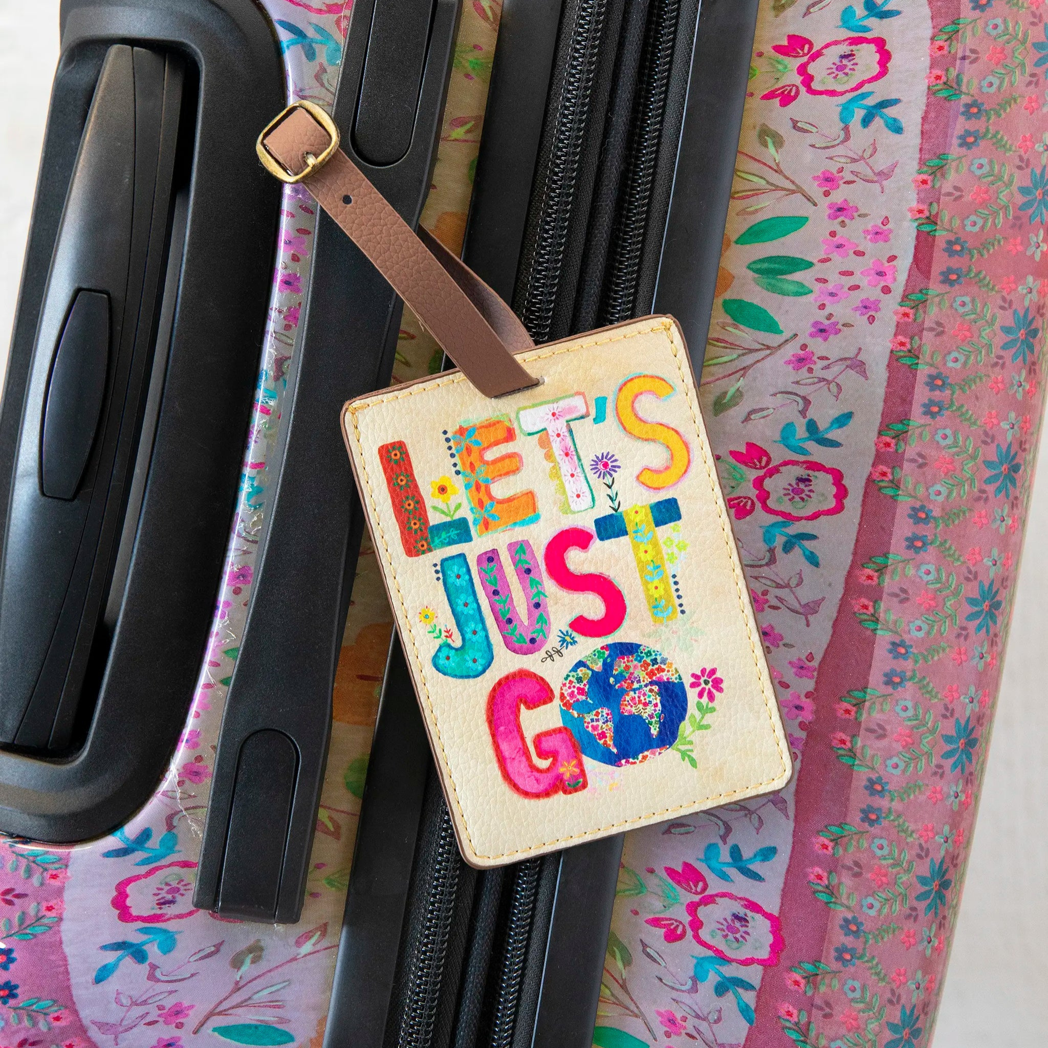 Natural Life Travel Happy luggage tag featuring "Let's Just Go" design in vibrant colors against a white background.