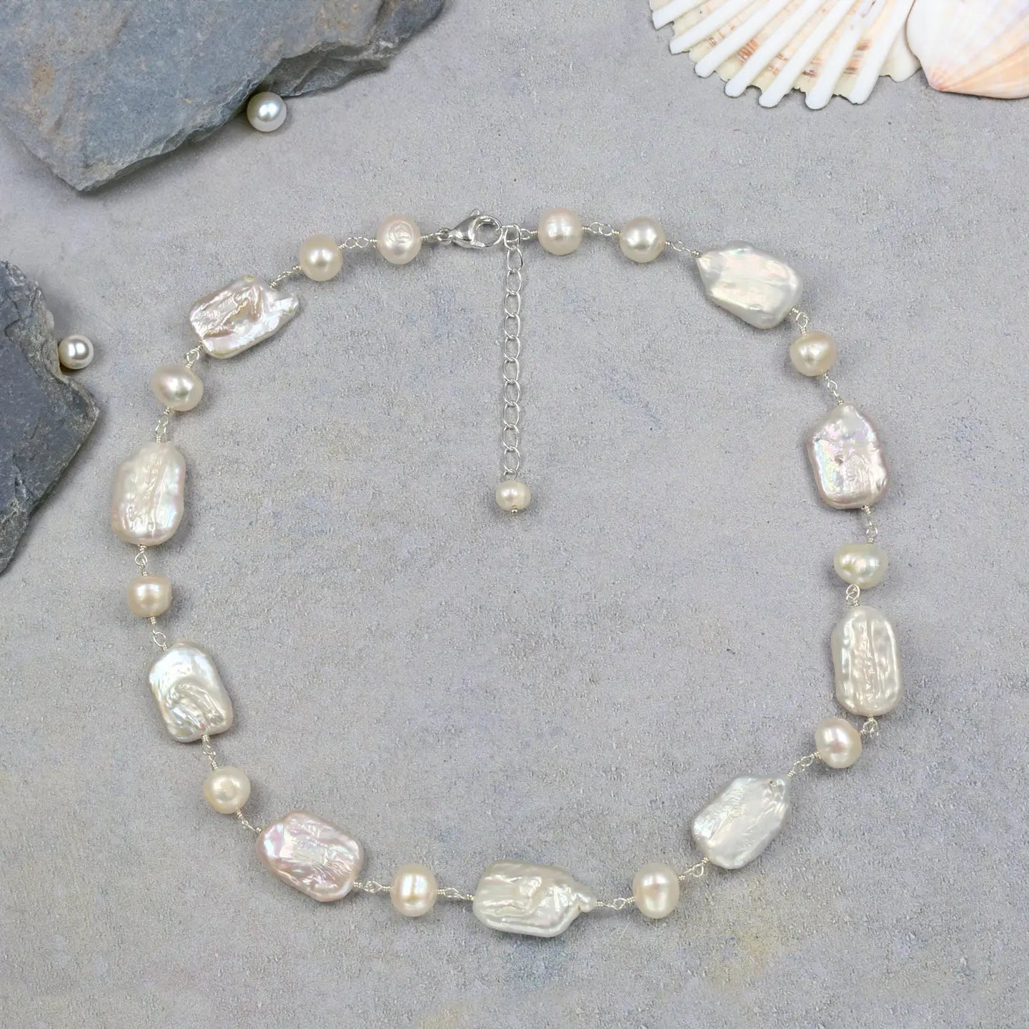 Pearl necklace on a gray surface with shells in the background