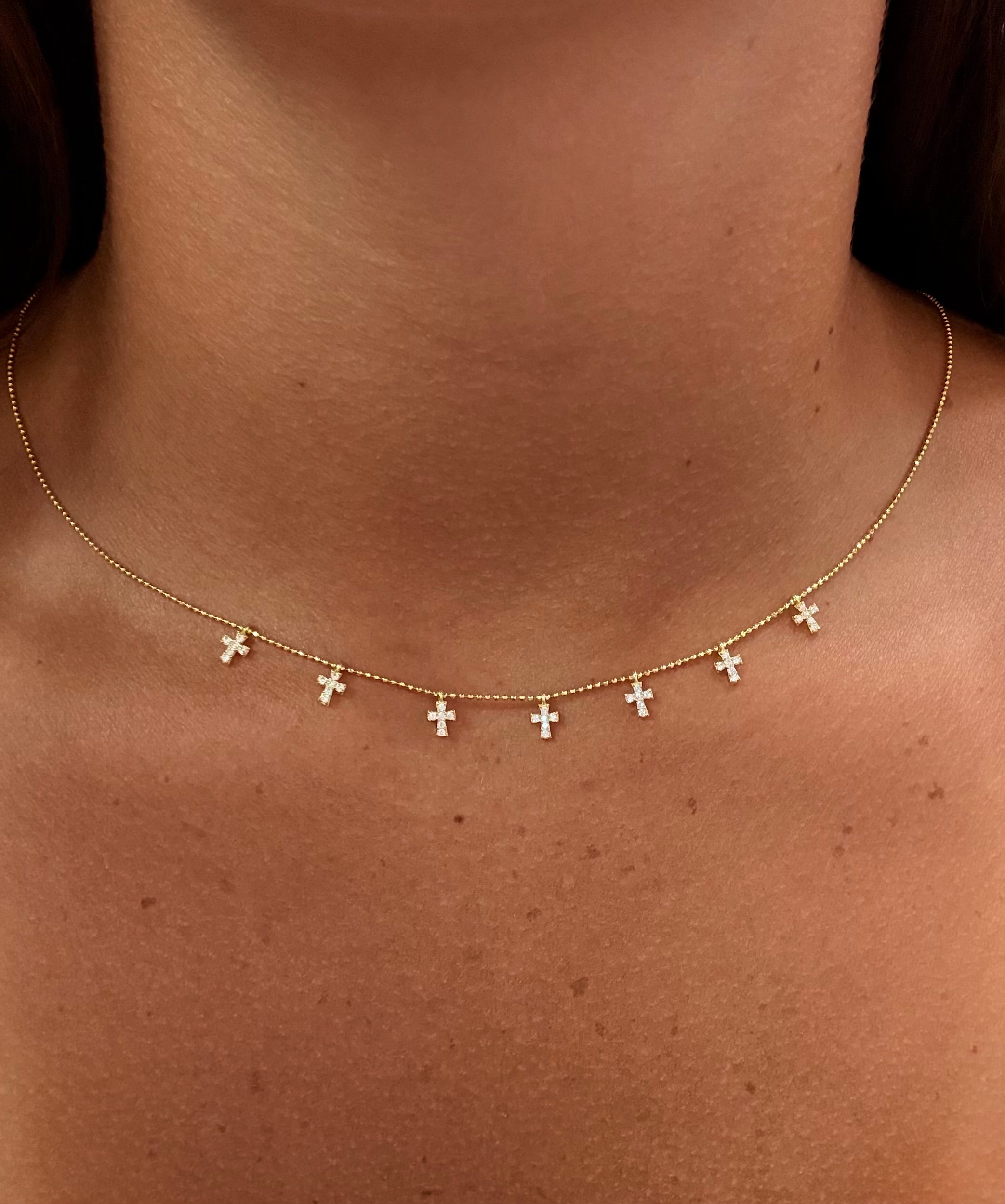 Rose gold necklace with small crosses on a person's neck