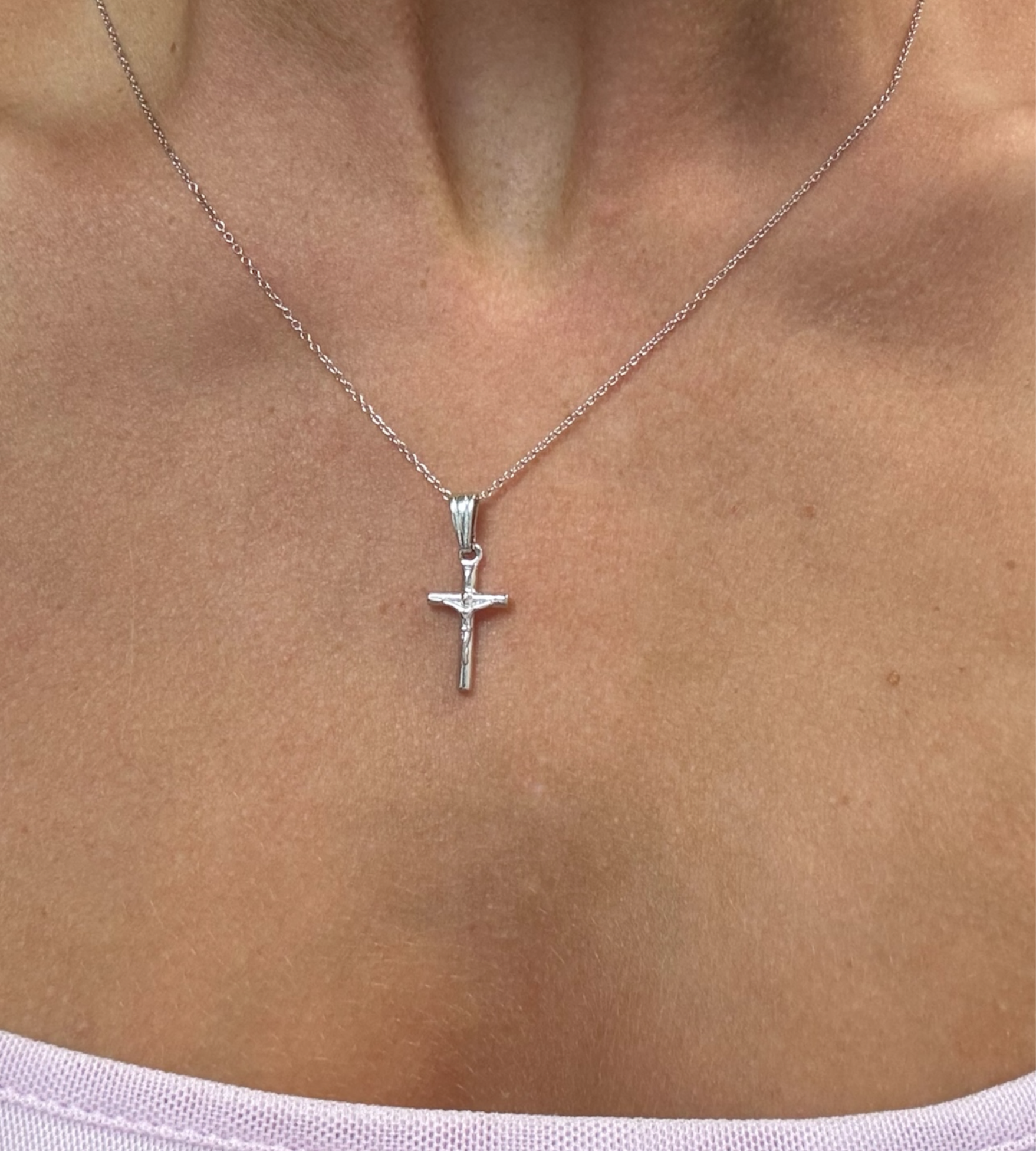 Silver cross necklace on a person's neck