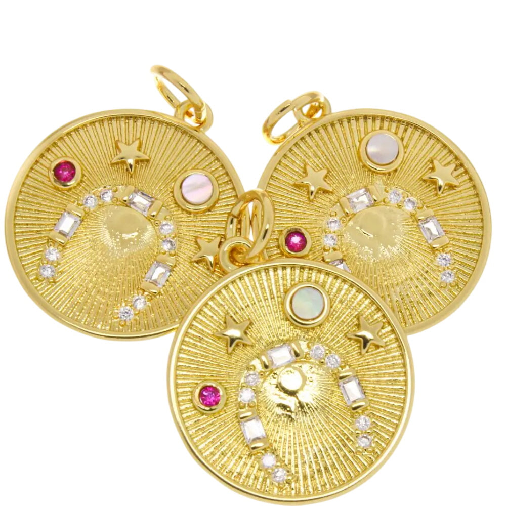 Gold horseshoe charm with pink CZ and moonstone, showcasing intricate design and vibrant gemstones.