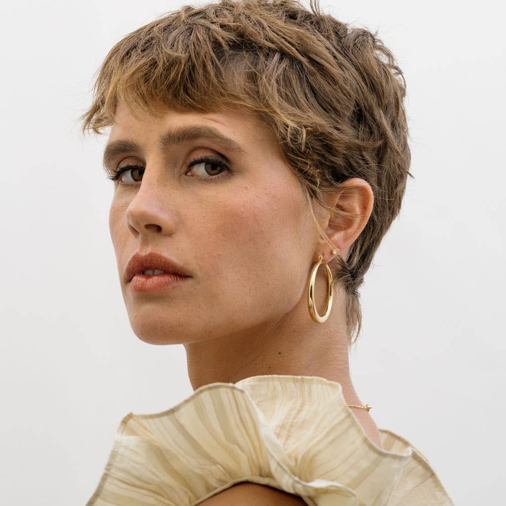 Large Maria hoops earrings by Amano Studio featuring bold, circular gold hoops with a smooth finish on a white background.