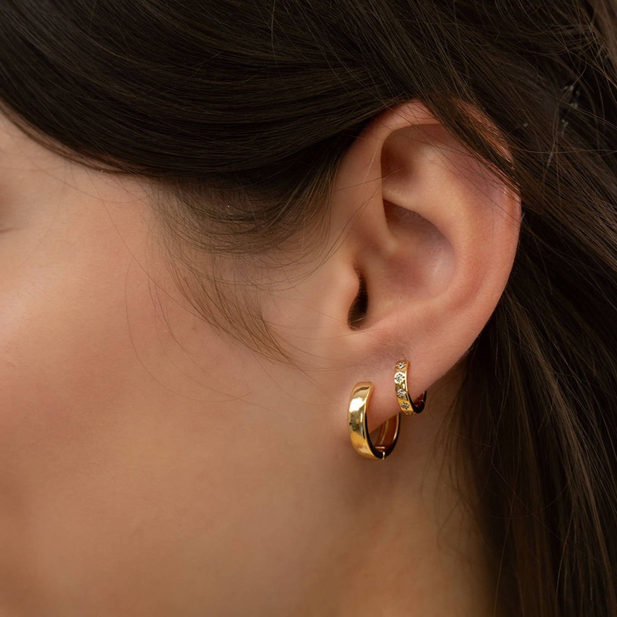 Amano Studio 15mm gold hoop earrings showcasing smooth, shiny circular earrings on a plain background.