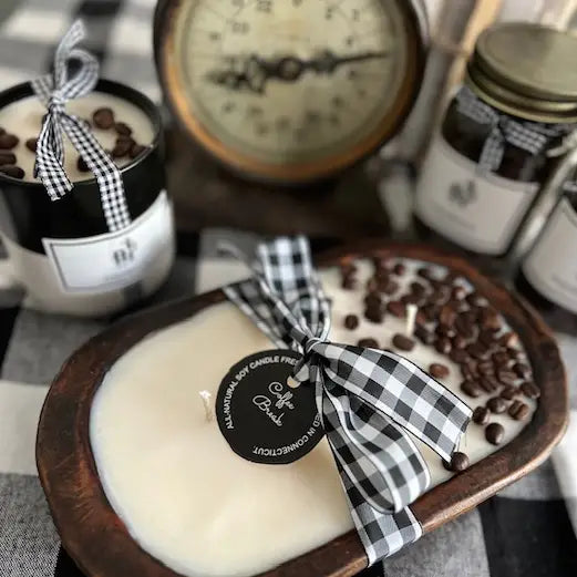 Candle with coffee beans and a checkered ribbon on a wooden plate, surrounded by jars and a clock.