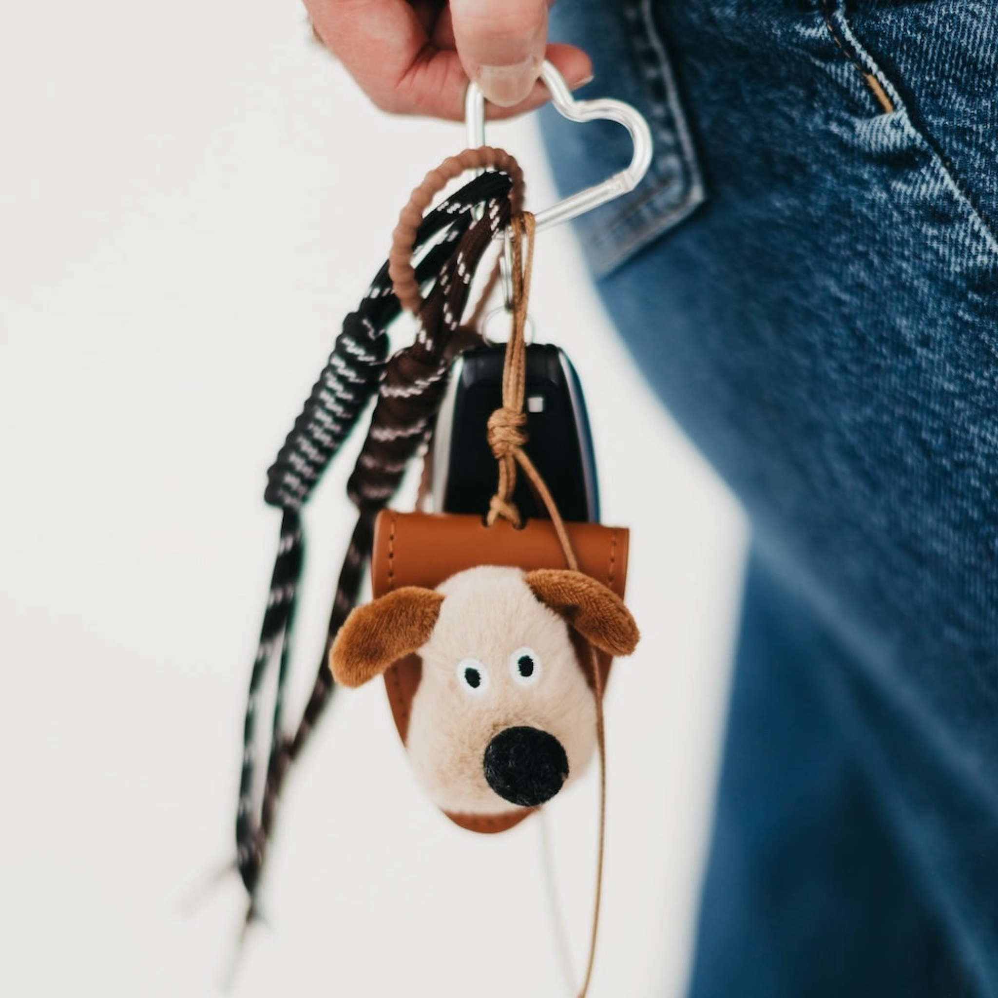 Dog-shaped keychain attached to a bag with a blurred background