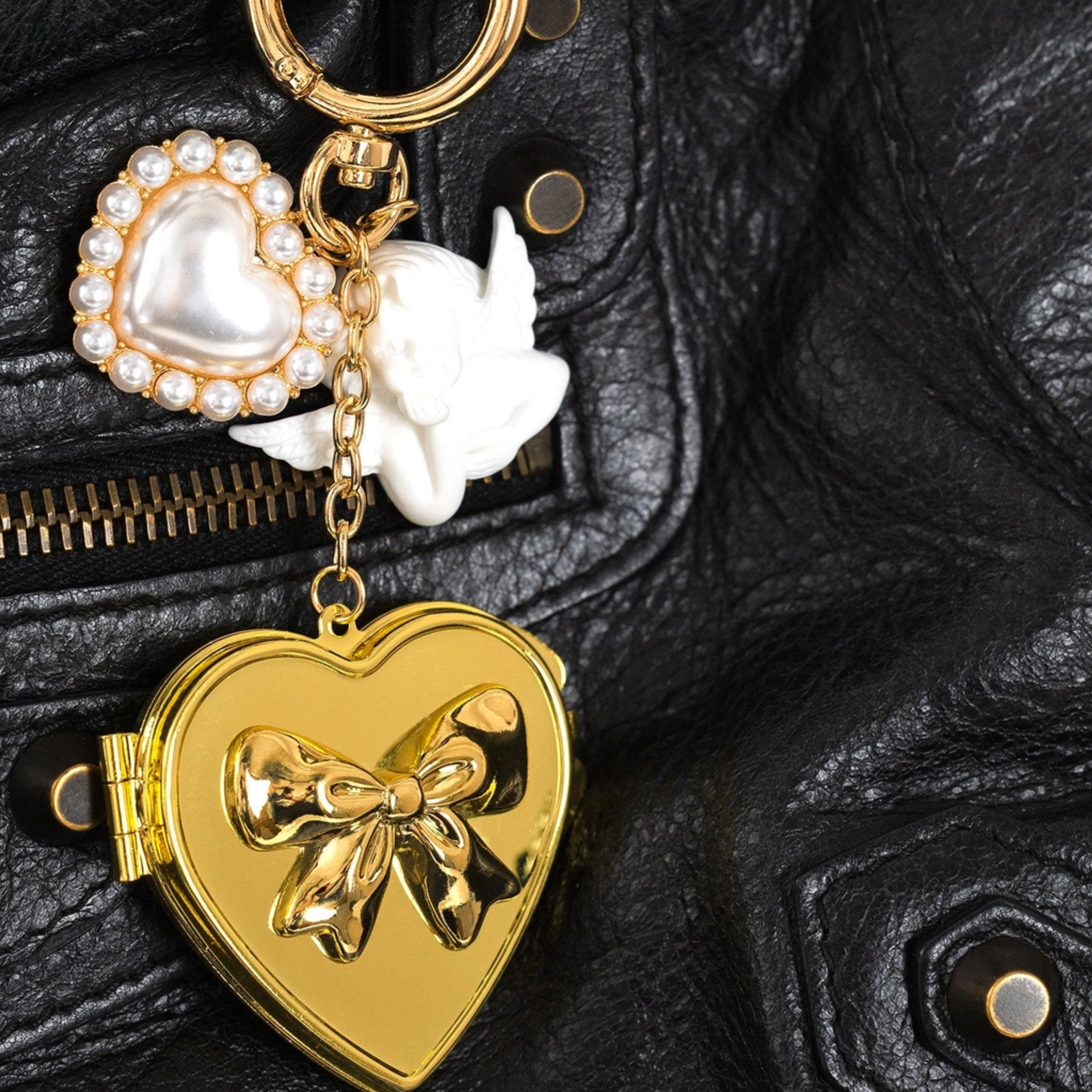 Gold heart-shaped keychain with a bow design on a black textured surface