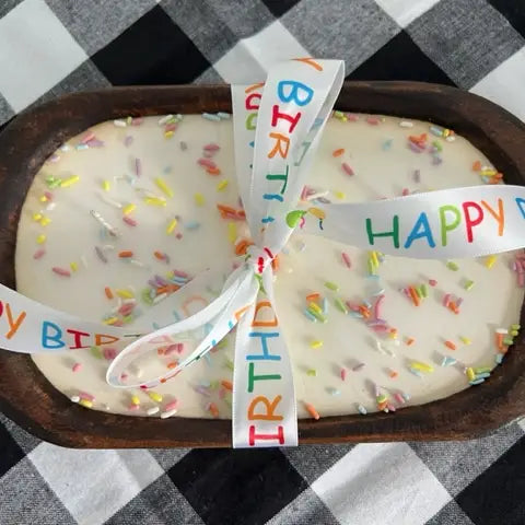 Two birthday-themed candles with colorful sprinkles and 'Happy Birthday' ribbons on a checkered background.